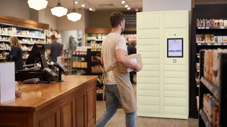 Retail staff member carrying a parcel past a StaticMile locker bank